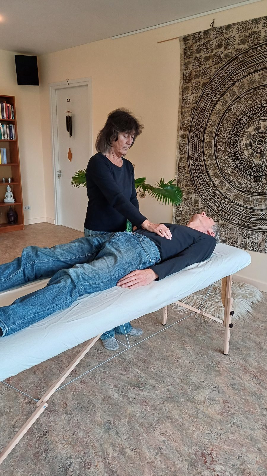Jolanda Verburg geeft een reiki behandeling aan iemand op de behandeltafel in de studio in Beusichem
